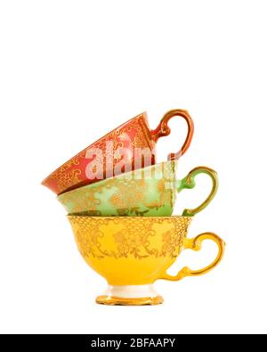 Pile de trois tasses à thé chinoises vintage aux couleurs vives en jaune, vert et rouge avec un joli motif fleuri en or. Isolé sur fond blanc Banque D'Images