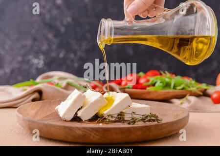 Verser de l'huile d'olive sur du fromage feta savoureux sur la plaque Banque D'Images