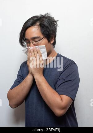 L'homme asiatique qui a froid ou la grippe, il tousse à la gorge claire avec la main tenant papier de tissu de fermeture de sa bouche isolé sur le fond blanc maladie et Banque D'Images