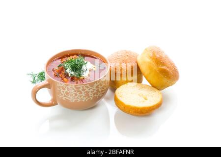 soupe chaude aux betteraves à la crème sure, aux herbes et aux petits pains dans un bol en céramique isolé sur fond blanc Banque D'Images