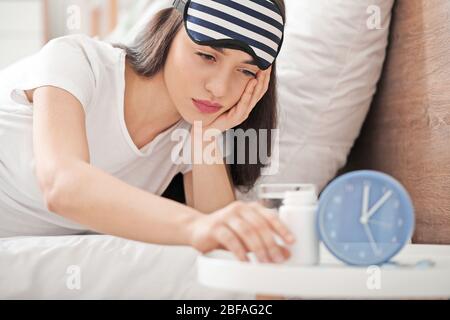 Jeune femme avec des pilules pour insomnie dans la chambre Banque D'Images