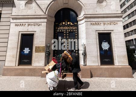 Un homme sans abri poussant son panier d'affaires tourne pour regarder la boutique de bijoux Harry Winston sur la Cinquième Avenue, une image puissante de l'inégalité des revenus Banque D'Images