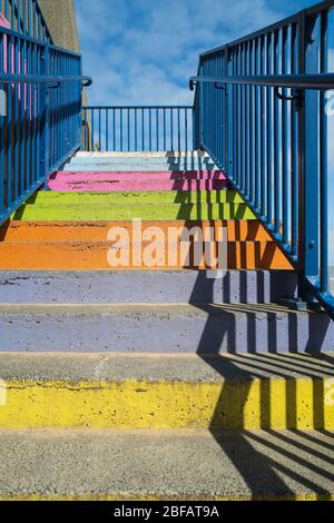 Les marches en béton ont peint des couleurs arc-en-ciel vives avec une rambarde bleue et un motif d'ombre fort Banque D'Images