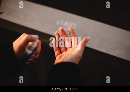 Gros plan sur la jeune femme appliquant un antiseptique désinfectant pour les mains tout en désinfectant les mains debout à l'extérieur en prenant la rampe en ville Banque D'Images