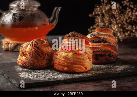 Kraffins aux raisins secs, fruits confits et graines de pavot, arrosés de sucre en poudre. Banque D'Images