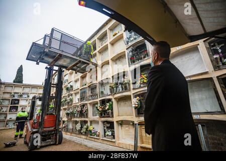 Un gravedigger exploite un chariot élévateur avec son partenaire se préparant à fermer la niche pendant les funérailles. Le Covid-19 rend les funérailles difficiles, la situation exige que les travailleurs portent des masques et soient forcés de limiter l'accès, dans certains cas les cérémonies sont sans membres de la famille. Banque D'Images