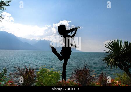 Montreux, Suisse - 14 septembre 2017 : silhouette de fille avec violon sur la promenade du lac Léman (lac Léman) devant les montagnes Banque D'Images