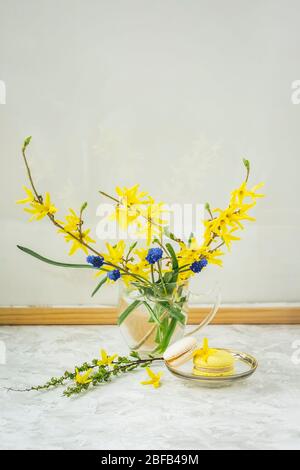 Bouquet de couleurs près d'un mur de verre dans un cadre en bois, léger reflet et deux macarons, bracfest romantique, matin lumineux Banque D'Images