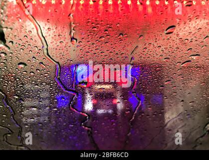 17 avril 2020, Hessen, Francfort-sur-le-Main: Des perles d'eau se sont formées sur le pare-brise d'une voiture de tourisme conduite à travers un lavage de voiture éclairé par des lampes colorées. Photo: Arne Dedert/dpa Banque D'Images