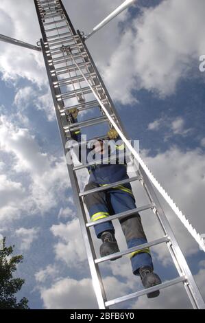 Contre un ciel bleu un chasseur de feu de Hertfordshire Fire & Rescue Service, Royaume-Uni, en train de transformer une échelle en un bâtiment élevé. . En décembre 2005, le HFRS a traité Banque D'Images