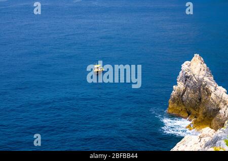 Bateau jaune sur l'eau bleu sombre de Grotta di Lord Byron près de la côte avec falaise de roche, ville de Portovenere, mer Ligurienne, Riviera di Levante, parc national C Banque D'Images