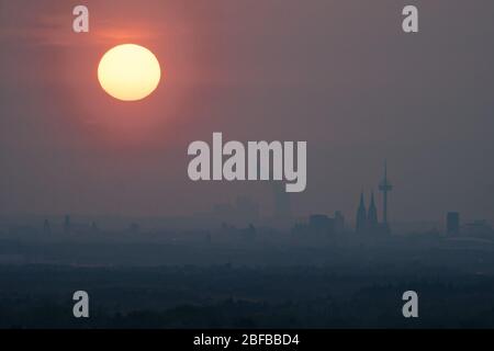 Cologne, Allemagne. 17 avril 2020. Le soleil se couche derrière les toits de Cologne. En arrière-plan, vous pouvez voir la centrale électrique de lignite Niederaussem. Crédit: Henning Kaiser/dpa/Alay Live News Banque D'Images