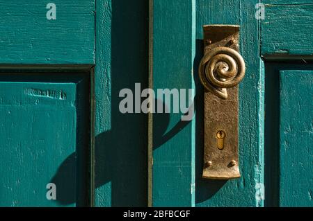 ancien bouton de porte en laiton avec poignée en boucle sur porte en bois verte Banque D'Images