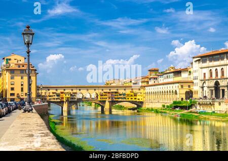 Pont en pierre Ponte Vecchio avec bâtiments colorés maisons sur le bleu de la rivière Arno reflétant l'eau et la promenade de remblai dans le centre historique de Flor Banque D'Images