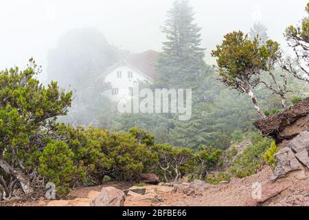 Une maison blanche avec un toit carrelé dans les montagnes parmi les nuages. Banque D'Images