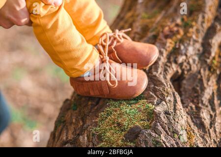 les pieds des enfants en chaussures brunes sur le fond d'un arbre au printemps Banque D'Images