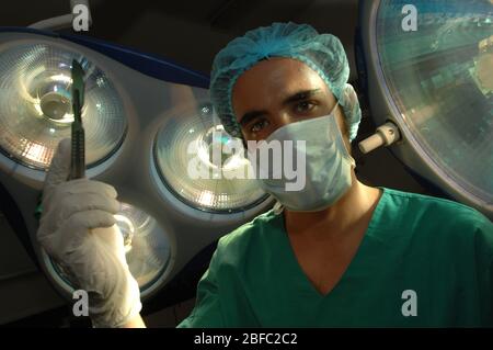 Gros plan sur un chirurgien de l'hôpital qui tient un scalpel sous les lampes du théâtre d'opération Banque D'Images