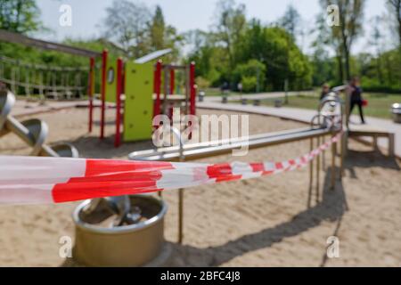 Le ruban rouge et blanc de mise en garde d'alarme avec le texte « Polizei » signifie police en allemand, enveloppé autour de jouets fermés pour aire de jeux en plein air pendant les distances sociales. Banque D'Images