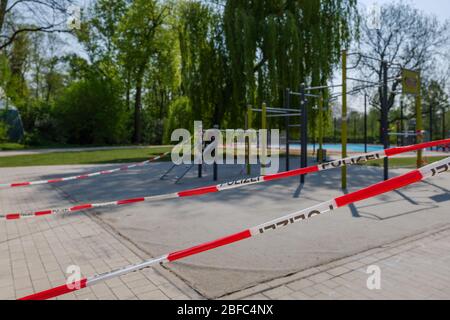 Le ruban rouge et blanc de mise en garde d'alarme avec le texte « Polizei » signifie police en allemand, enveloppé autour de jouets fermés pour aire de jeux en plein air pendant les distances sociales. Banque D'Images