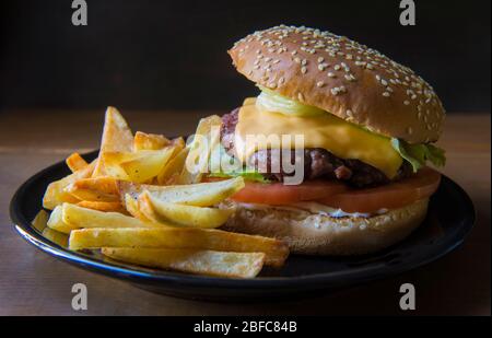 Un hamburger maison sans ketchup, avec des frites sur le côté, sur une table rustique en bois, concept de nourriture appétissant Banque D'Images