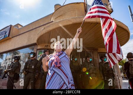 Huntington Beach, Californie, États-Unis. 17 avril 2020. Une foule de personnes se rassemblent vendredi sur la rue Main pour protester contre la fermeture du coronavirus (COVID-19). Plus de 100 manifestants défiant les commandes de séjour à domicile se sont réunis au cœur du centre-ville de Huntington Beach vendredi après-midi, se ralliant à la fin des restrictions imposées aux entreprises et aux rassemblements publics. Crédit: Kevin Warn/ZUMA Wire/Alay Live News Banque D'Images