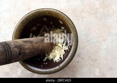 Une image montrant un mortier rempli d'ail finement pilé, avec le pilon toujours à l'intérieur. Banque D'Images