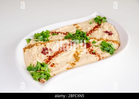 Humus maison sur une plaque blanche avec tahini, épicé, huile d'olive, citron, persil et pois chiches. Cuisine arabe, apéritif - délicieux humus. Mise au point sélective Banque D'Images