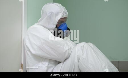 Gros plan. Homme épuisé médecin portant un costume de danger assis contre le mur. Prise de vue professionnelle en résolution 4 K. 054. Vous pouvez l'utiliser, par exemple dans votre commerc Banque D'Images