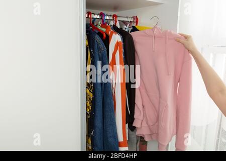 Femme choisit des vêtements dans le placard et prend le hoody rose Banque D'Images