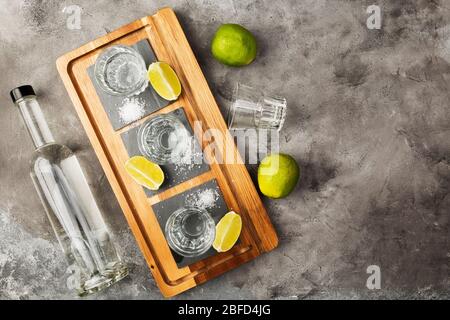 Bouteille de Tequila et doses, limes, sel sur planche en bois. Vue de dessus, espace de copie Banque D'Images