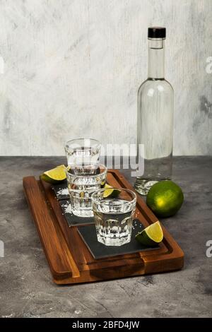 Bouteille et doses de Tequila, limes, sel sur planche en bois Banque D'Images