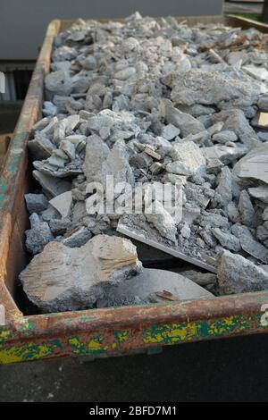 Débris de construction dans un grand, vieux, contenant rouillé. Des morceaux de mortier, du béton brisé et des séparateurs de bois remplissent tout le volume. Banque D'Images