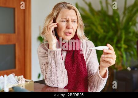 Portrait de la femme atteinte de maturité et malade en difficulté assise à la maison et est en appel.concept de fièvre, de fumée ou de virus. Banque D'Images