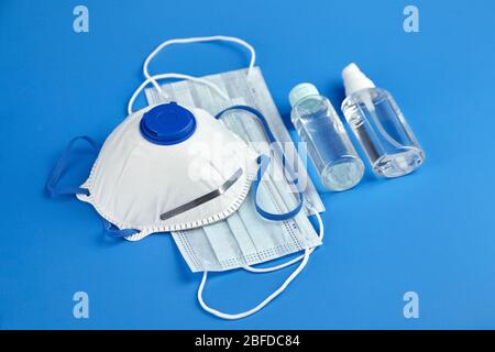 Désinfectant antibactérien pour les mains, masque respiratoire et masques chirurgicaux sur fond bleu. Masques jetables anti-poussière respirants. Protection contre le coronav Banque D'Images