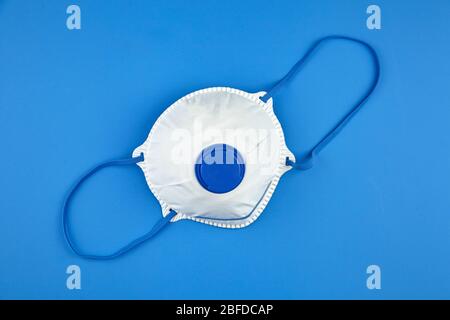 Masque filtrant sur fond bleu, vue de dessus. Respirateur N 95. Masque blanc FFP2, protection contre la pandémie de coronovirus COVID-19 Banque D'Images