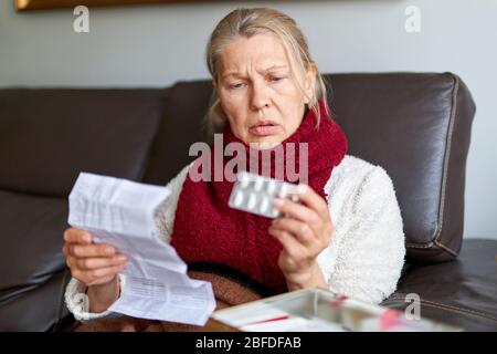 Femme mature prenant la médecine. Femme tenant le pack de Blister avec des pilules en main et lisant des instructions médicales. Femme aînée regardant l'instruction, tenir Banque D'Images