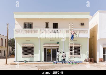 Trois hommes de la région peignant une maison de 2 étages à Nouakchott, en Mauritanie. Banque D'Images