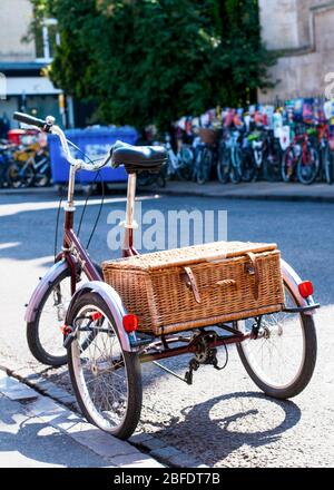 Un vieux tricycle / vélo avec un panier de paille dans une rue à Cambridge Banque D'Images