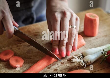 Couper et trancher les carottes de près. Girly mains préparer la nourriture dans la cuisine. Banque D'Images