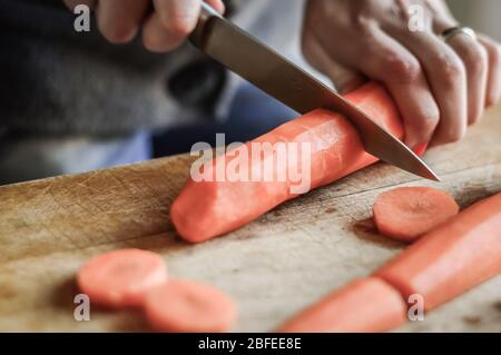 Couper et trancher les carottes de près. Girly mains préparer la nourriture dans la cuisine. Banque D'Images