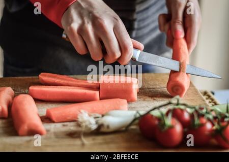 Couper et trancher les carottes de près. Girly mains préparer la nourriture dans la cuisine. Banque D'Images