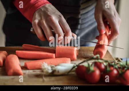 Couper et trancher les carottes de près. Girly mains préparer la nourriture dans la cuisine. Banque D'Images