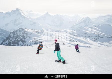Groupe de trois surfeurs de neige freeride, femmes et hommes, rouleaux et promenades planches de snowboard sur la piste de neige, et profiter dans la belle chaîne de montagnes des Alpes Banque D'Images