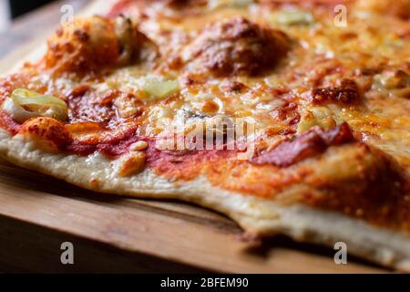 Pizza faite maison sur une planche de bois. Gros plan sur une pizza au levain fraîchement cuite Banque D'Images