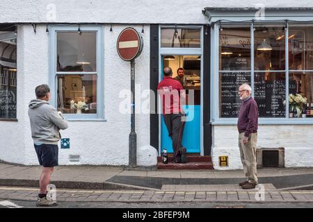 Trois clients qui maintiennent des distances sociales tout en attendant une pizza à emporter dans la petite ville galloise de Presteigne, Powys, Royaume-Uni, pendant l'épidémie Banque D'Images