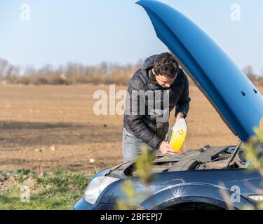 L'homme remplit le liquide de lave-glace Banque D'Images