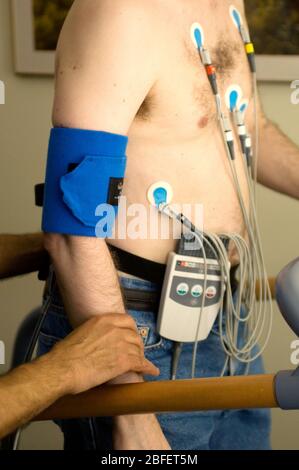 Un homme qui subit un test d'effort d'exercice marchant sur un tapis roulant tout en étant relié à l'équipement qui surveille sa fréquence cardiaque, respiration, pression artérielle, Banque D'Images