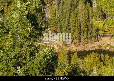 Des voitures longent El Portal Road par la Merced River dans le parc national de Yosemite, Californie, États-Unis. Banque D'Images