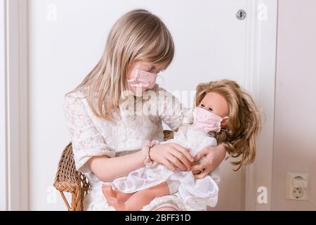 fille avec masque de protection covid 19 maison avec sa poupée Banque D'Images