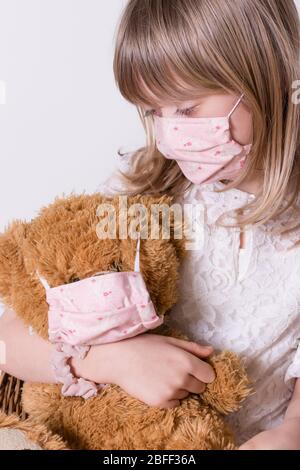 fille avec masque de protection covid 19 maison avec son teddybear Banque D'Images